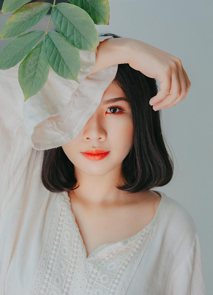 Serene portrait of a woman with leaves, perfect for beauty and nature themes. natural glow achieved with Korean-inspired makeup